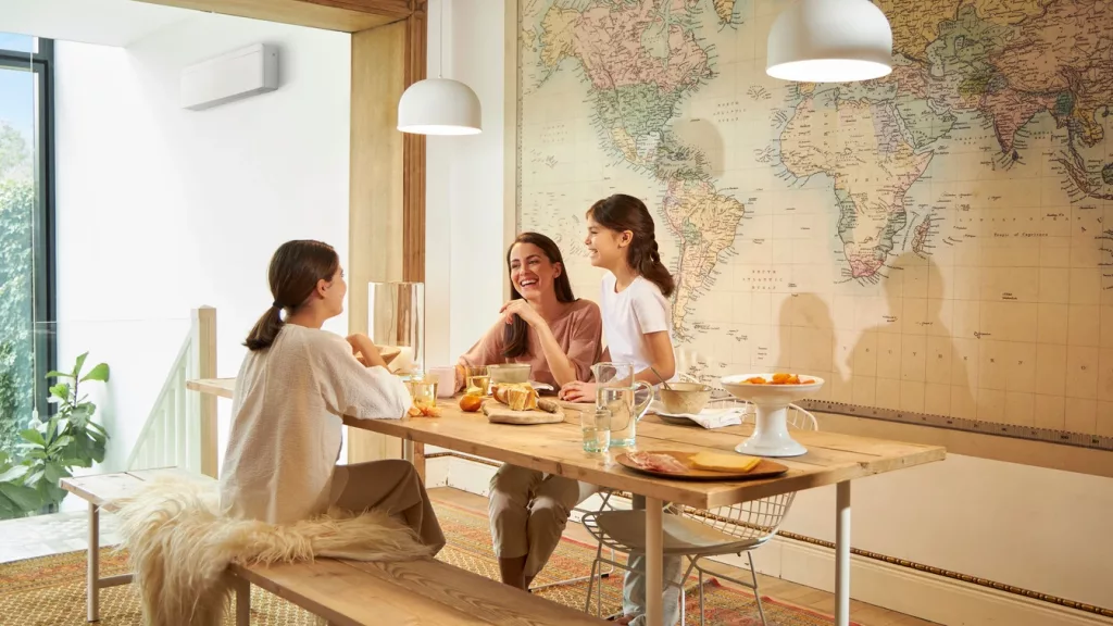 famille qui rit à la table du petit déjeuner dans une maison où il y a un climatiseur réversible mural daikin 